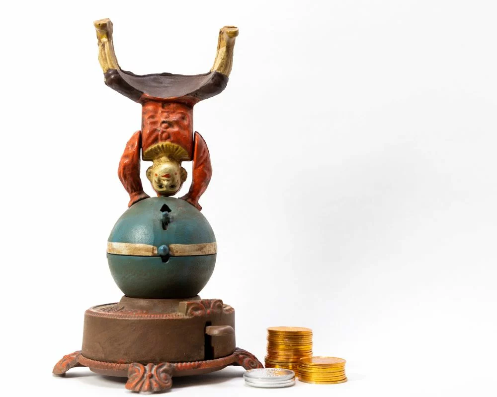 Antique cast iron wind-up clown on a ball coin bank with the clown standing on his head.