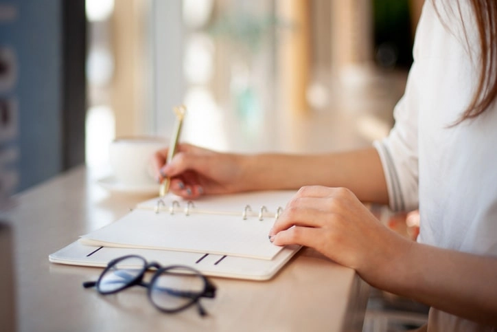 person writing in a planner
