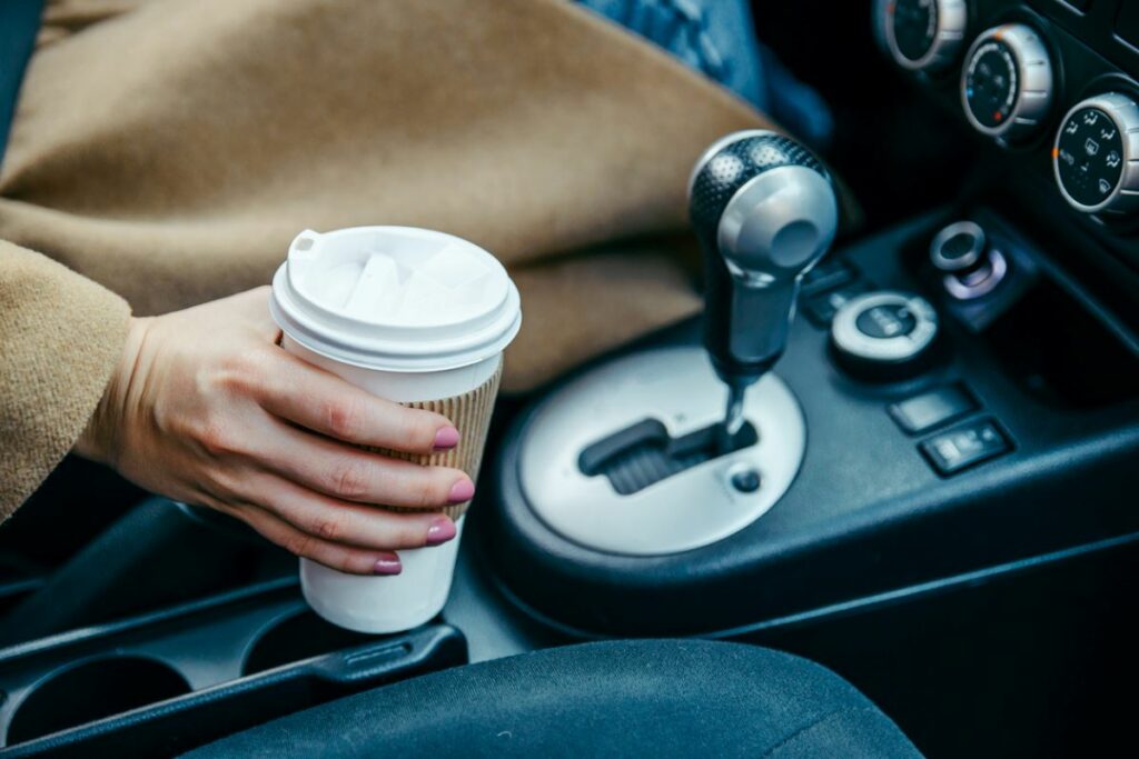 A woman sets her coffee cup down in her recently cleaned car cup holder.