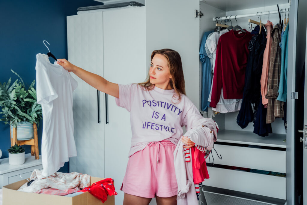 A college student declutters her closet by boxing up unwanted clothing