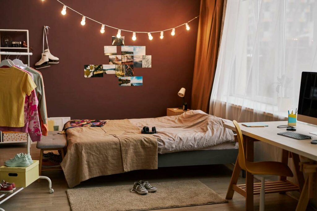 A college dorm room, complete with string lights, photos, and a messy closet.