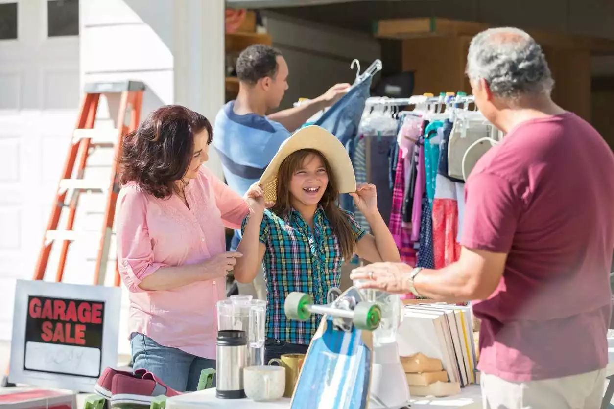 A child and mother smile while talking with a salesperson during a garage sale