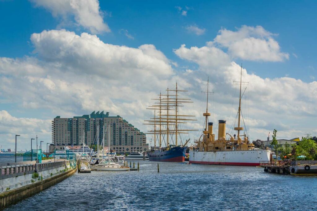 A view of the Delaware River waterfront, filled with historic ships and modern boats.