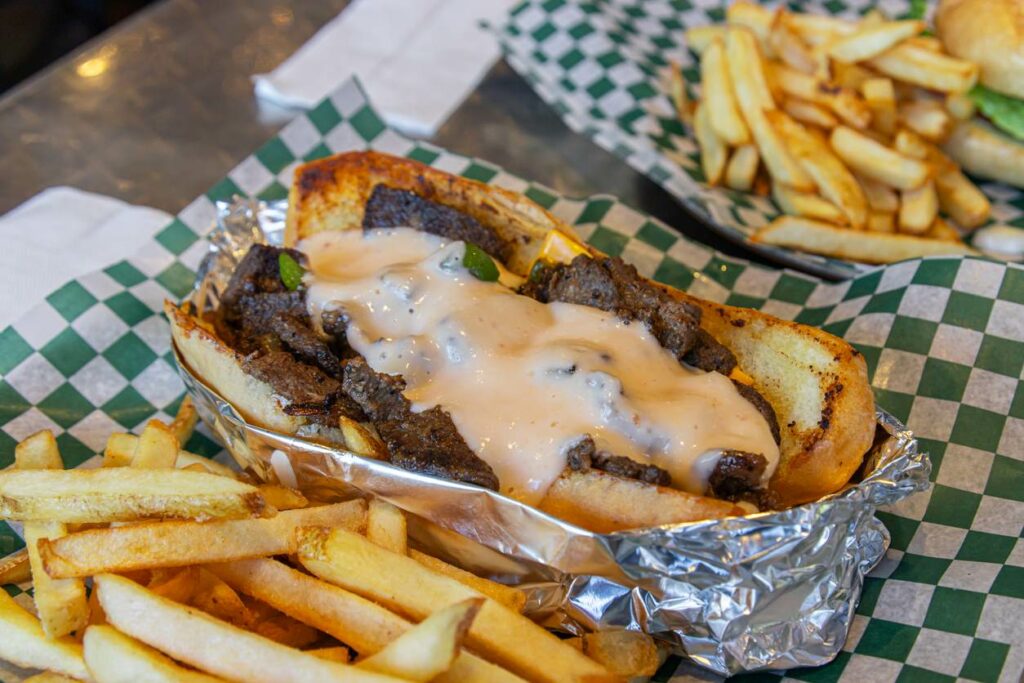 An iconic cheesesteak from Philadelphia consisting of melted cheese, sauteed onions, and shredded rib eye on a crusty roll